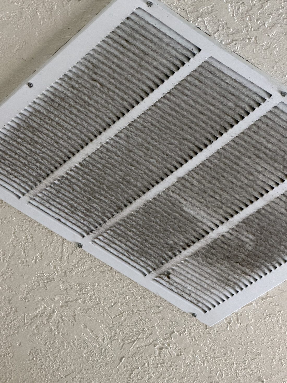 A return air vent thick with dust before cleaning